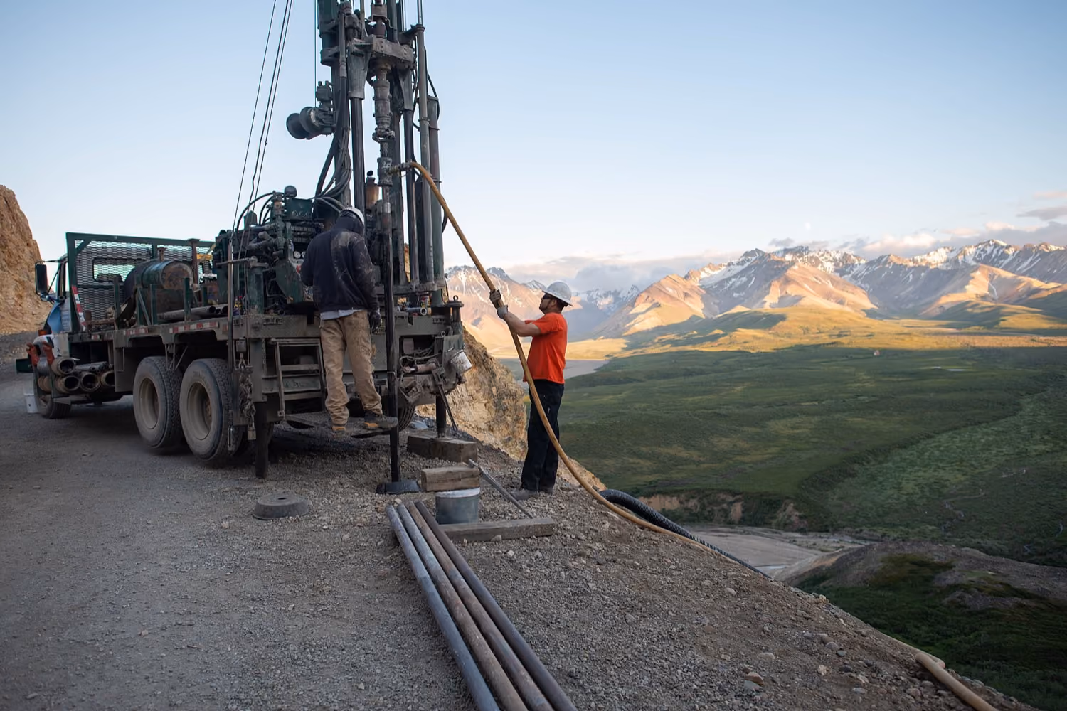 Drill crew operating an exploration rig on a hillside above open country