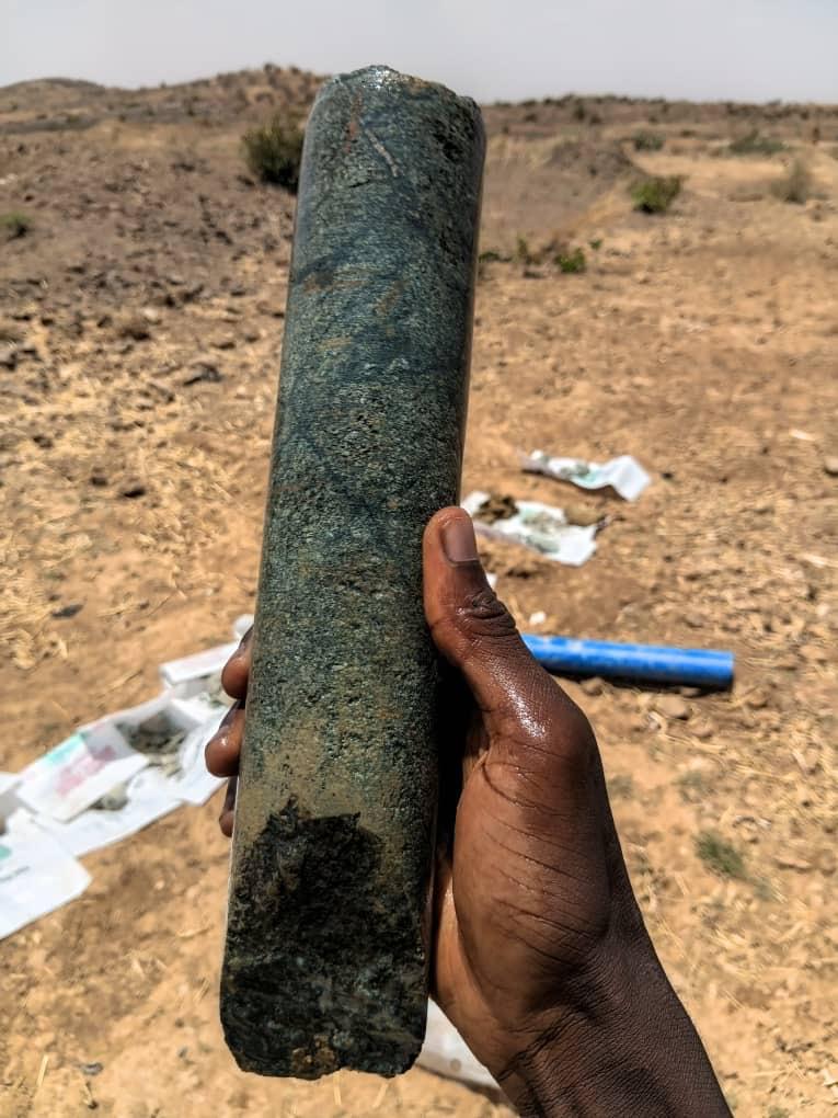 A recovered drill core sample held up for on-site visual inspection.